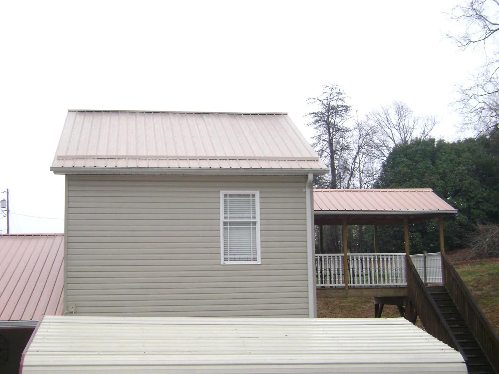 Tan metal roofs on a two story addition and attached porch, from a Roof Replacement job in Savannah